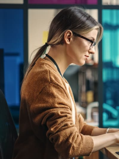 An IT employee works at a desktop station with three monitors.